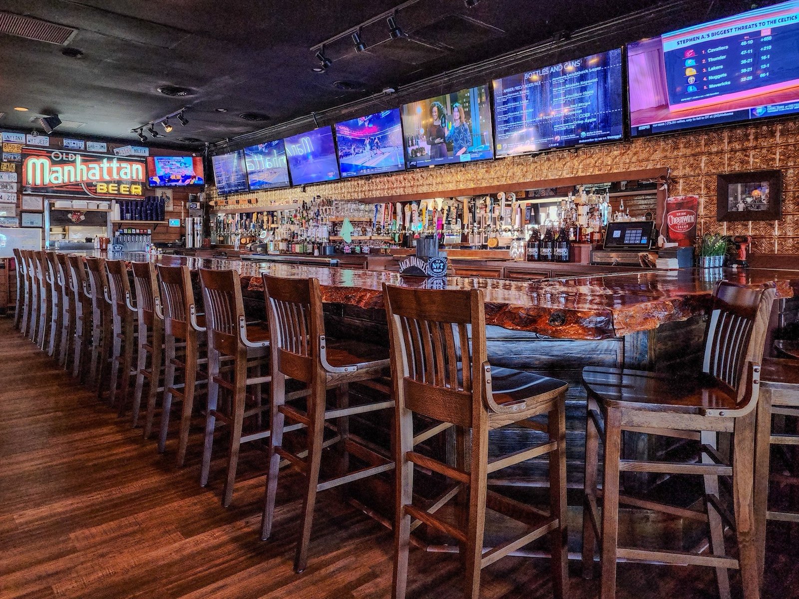 The long bar with wooden stools and a row of TVs